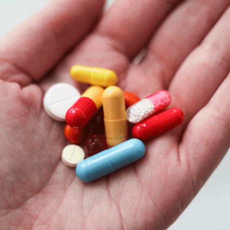 Close up of a hand holding assorted medicine