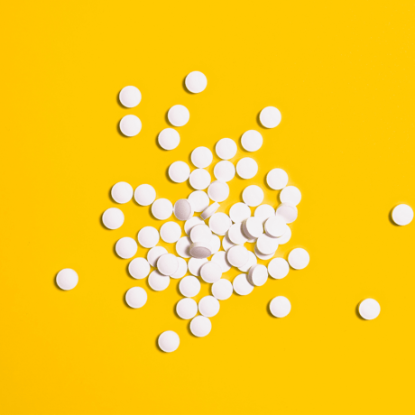 White pills laying on a yellow surface