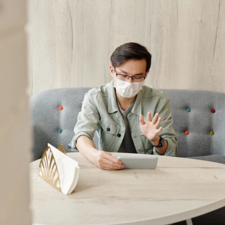 Man waving at his phone while sitting on a couch