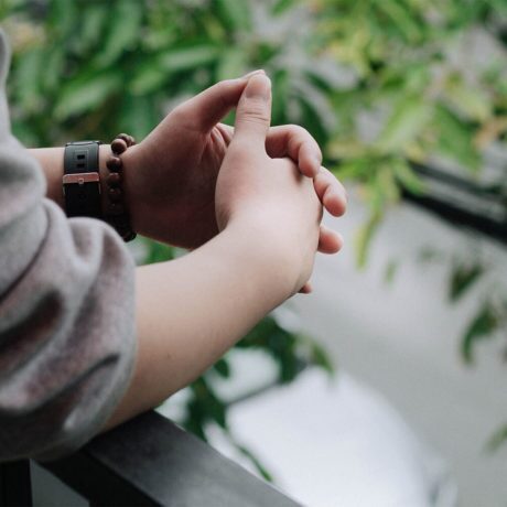 A woman leaning on a railing holder her hands together trying to recover from anxiety attack