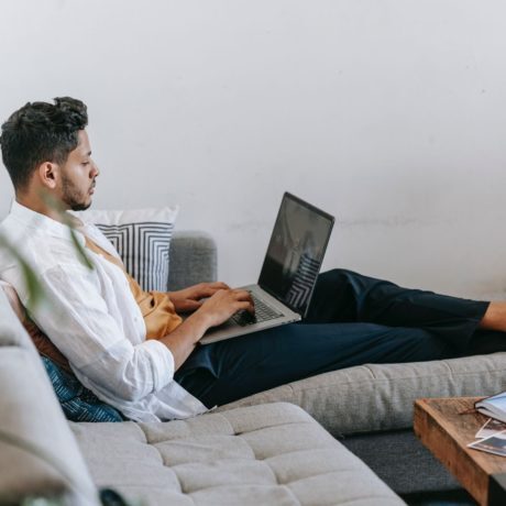 man sitting on a couch working on a laptop