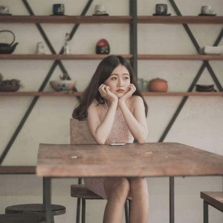 Woman holding her head up while sitting at a table in a store.