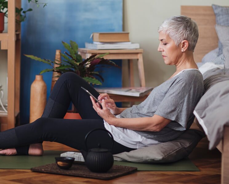 older woman sitting on the floor looking at phone